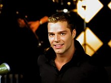 A screenshot from Livin' la Vida Loca music video, depicting Martin wearing a black shirt and performing in a nightclub