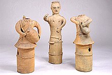 Three plain clay figures, featuring long, skirt-like columnar bases. The outer two figures are depicted playing drums. Only one figure, in the middle, has a head.