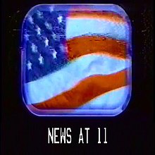 A windy American flag seen through a plane window; below reads "NEWS AT 11" in a font used by the US military.