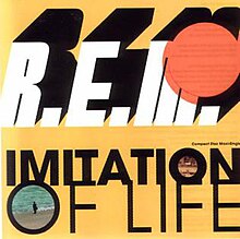 Against a yellow-orange background is the band's italicized name in white text, with a red-orange circle over the top-right quarter of the "M". Below is written "IMITATION OF LIFE" in black text, with an image in both O's. The first O contains a dry environment while the second O display a person standing on a beach. To the top-right of the song name is black text that reads "Compact Disc Maxi-Single".