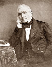 Photograph of middle aged white man in 19th century clothes; he is clean shaven apart from short side whiskers; his hair is short and white
