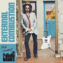 A photo of Mike Campbell leaning in a doorway next to a guitar