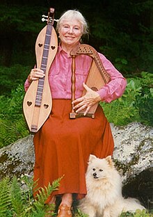Margaret holding her custom-luthiered MacArthur Harp and mountain dulcimer with heart-shaped soundholes