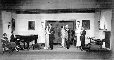large room with young man at a grand piano accompanying three dancing couples