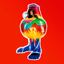Björk is depicted in a metallic sculptural costume in the shape of a "fat" bottle with feet, coloured brightly in red, yellow, pink, green and blue, in front of a red background. The sculpture has a big pearl on one of its sides and a hole that shows Björk's head.