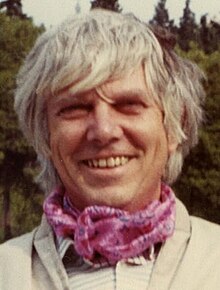 Man with white hair wearing a scarf