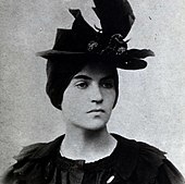 young white woman with dark hair in extravagant hat