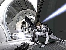 A horizontally rectangular video game screenshot that is a digital representation of a space station. A woman in a white and grey suit holding a large black gun ducks underneath a blue beam of light.