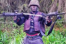 Lekeaka Oliver posing with two rifles in his ad hoc military uniform